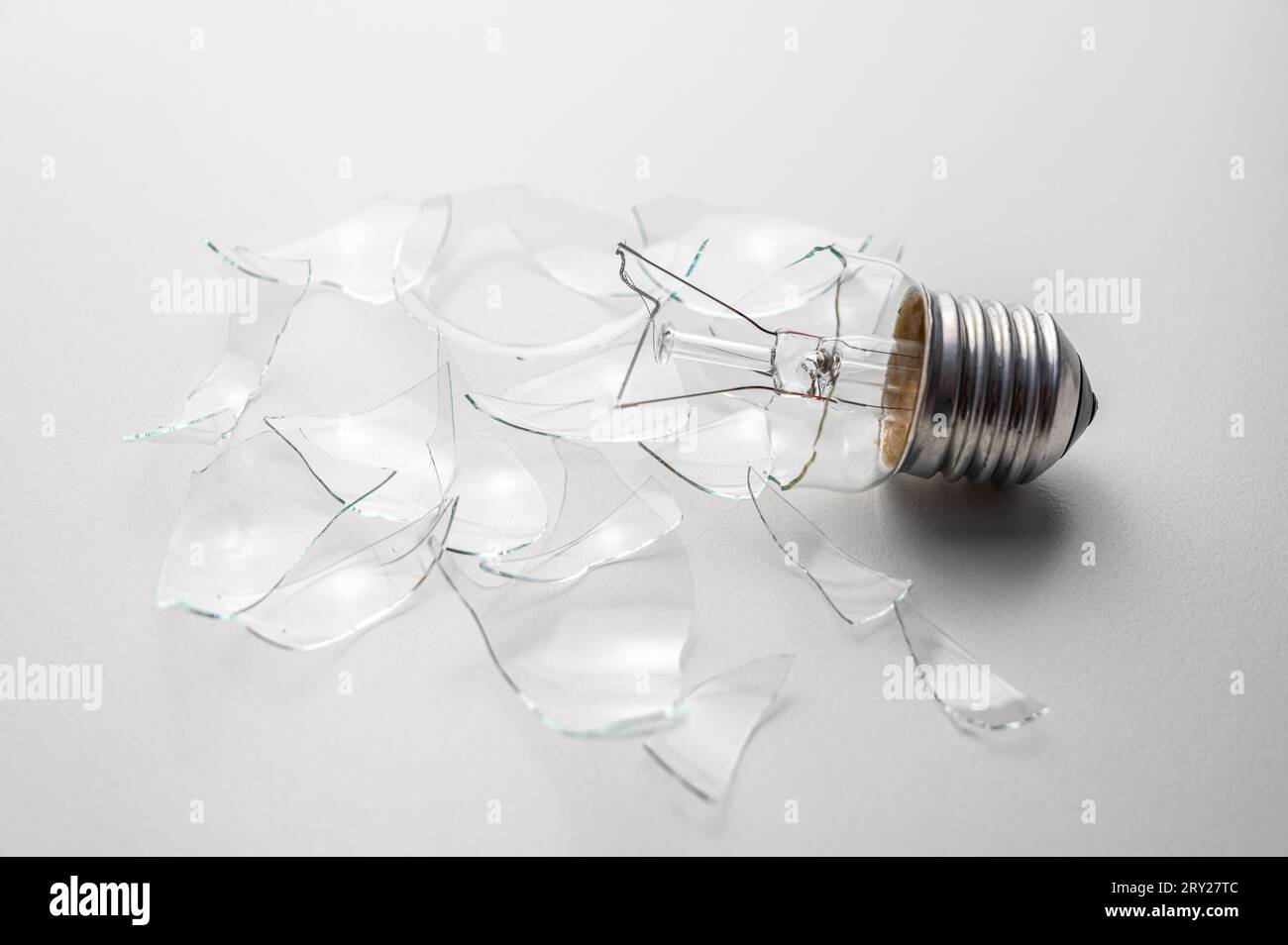 Broken light bulb, with shards of transparent glass around it, on a