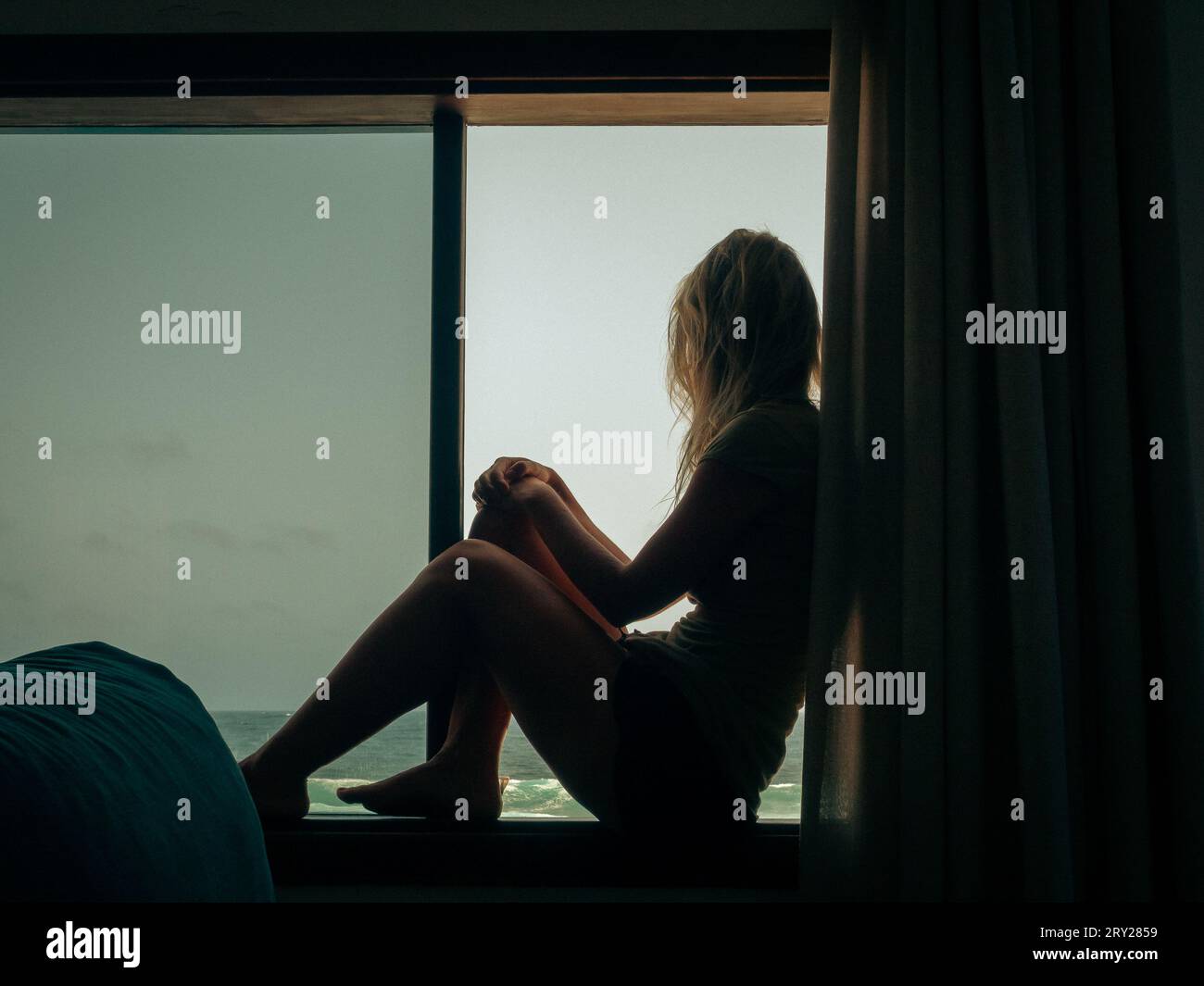 Silhouette of a woman looking at the sea from a window Stock Photo