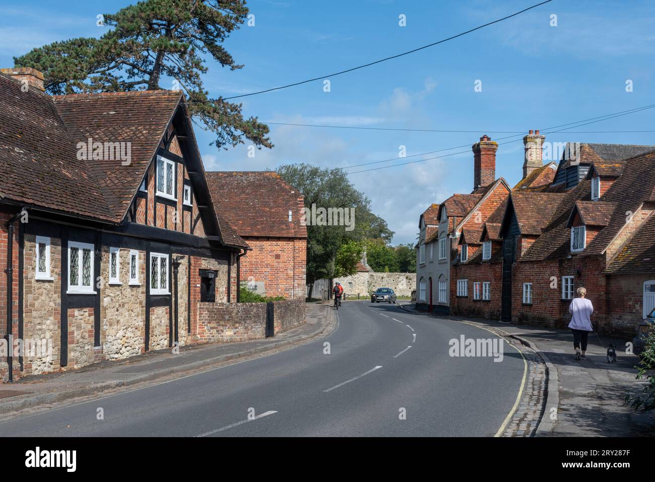 Beaulieu village in the New Forest, Hampshire, England, UK - street view with Beaulieu Mill on the right and cyclists Stock Photo