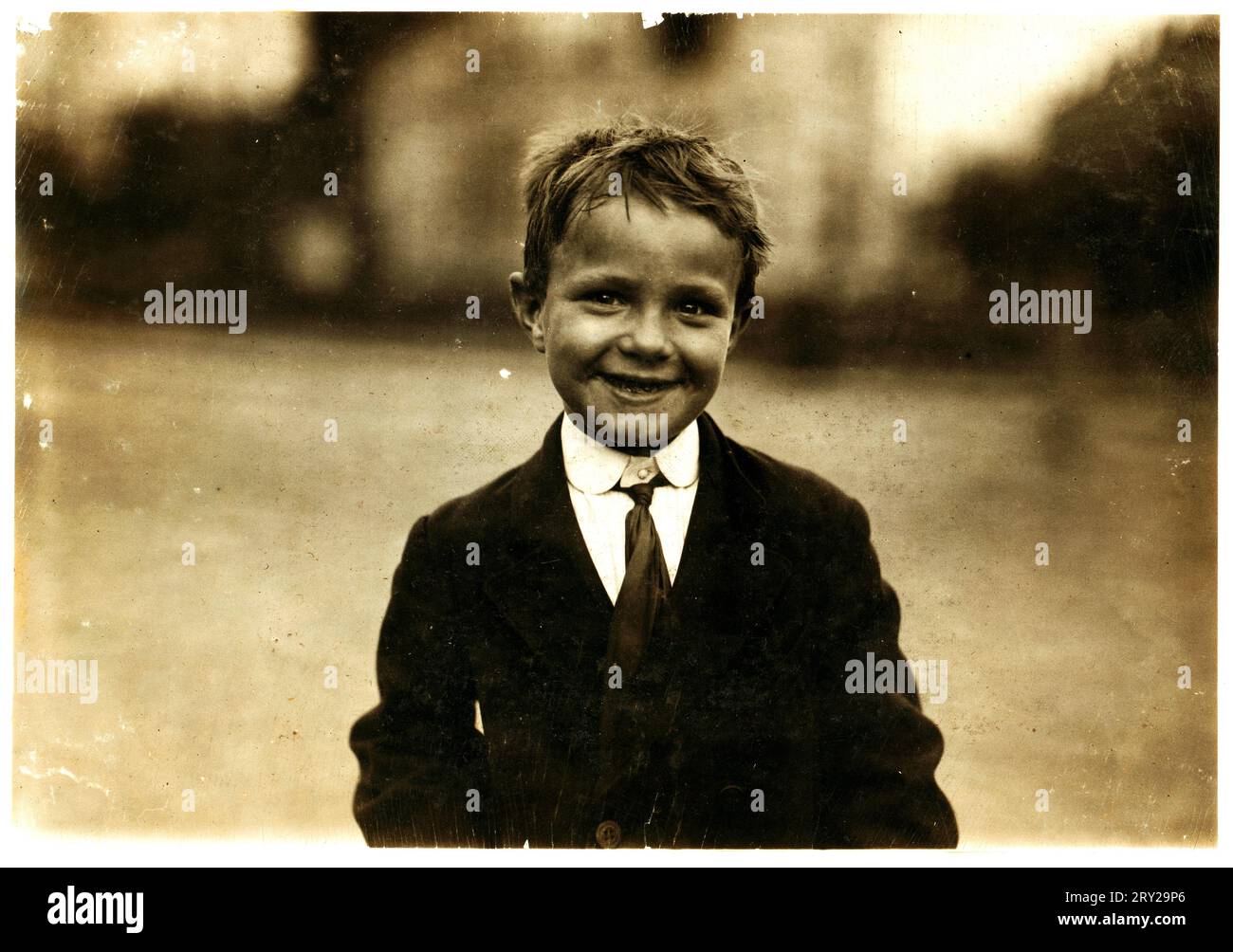 Lewis Hine: Tootsie, six years, newsboy, Washington, D.C., 1912  Tootsie, six yr. old news-boy, sells every day and Sunday for a young uncle who had to spend a good deal of his time driving Tootsie back on the job. Stock Photo