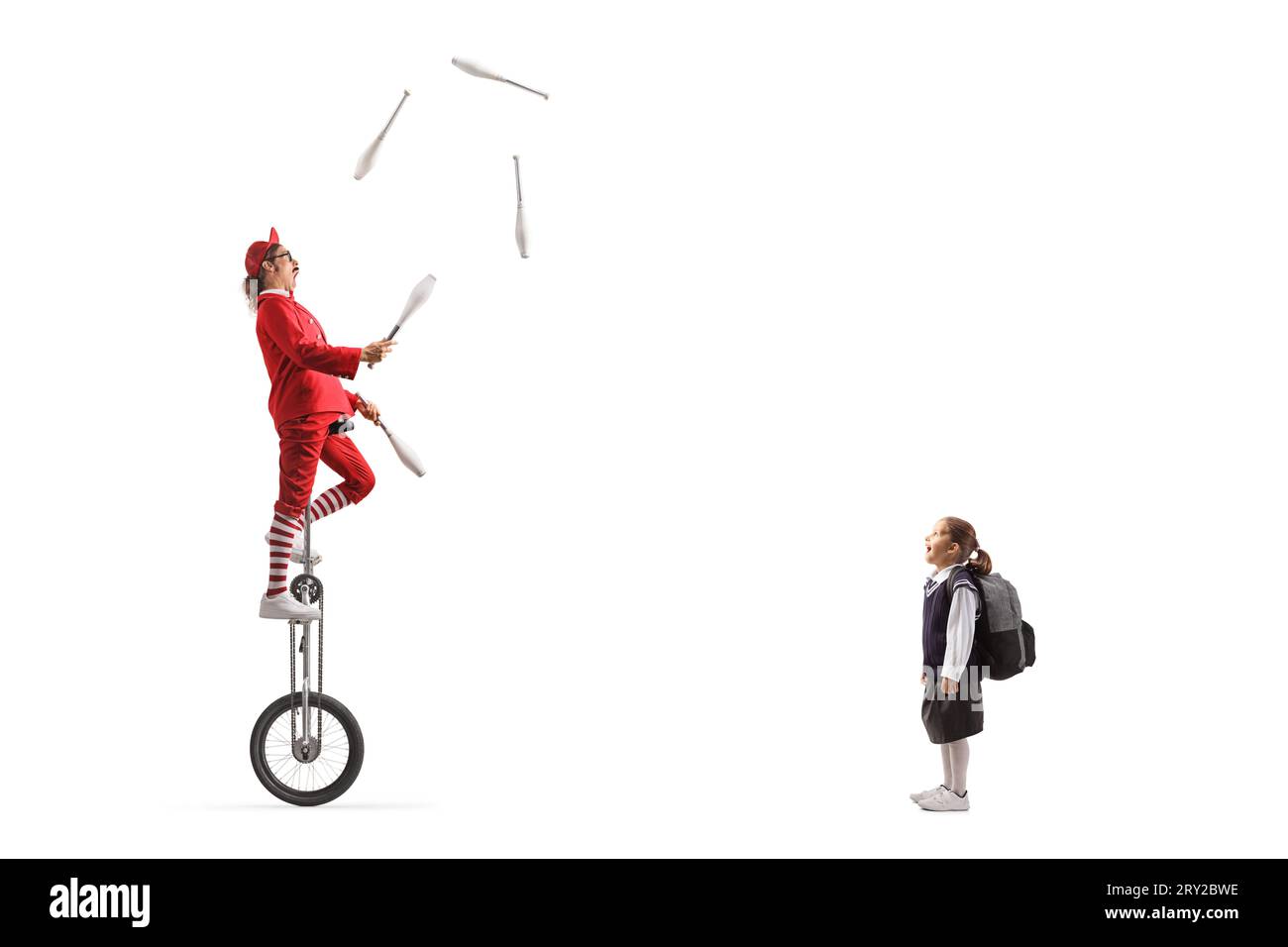 Surprised schoolgirl watching an acrobat riding a giraffe unicycle and juggling isolated on white background Stock Photo