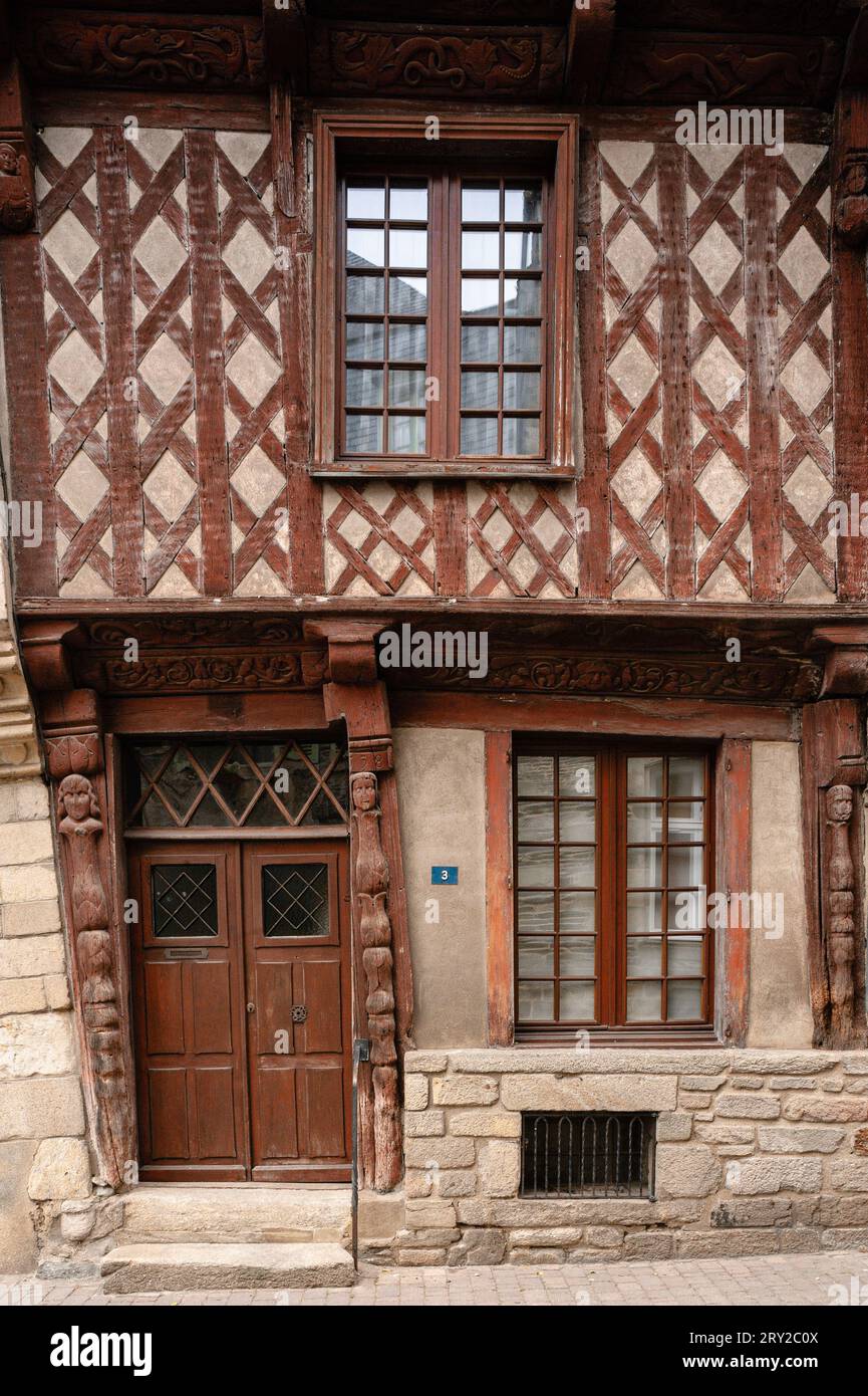 House dated 1538 in Josselin, Morbihan, Brittany, France, reputed to be the oldest house in the town.  The upper part of the property has diamond-shaped timber framing.  On the ground floor, spindle pilasters are topped by carved faces.  The upper and lower bressummer or load-bearing wooden beams are decorated in bas-relief by animals, including a dog chasing a fox, fantastical creatures, including dragons, and a human face surrounded by foliage. Stock Photo