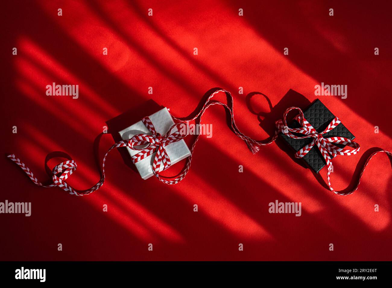 From above small colored cardboard boxes with red bow placed on red background Stock Photo