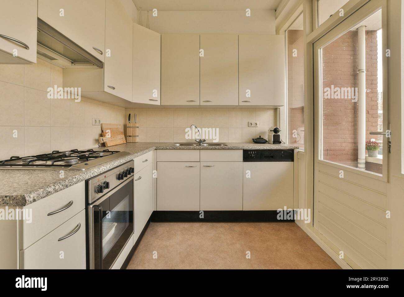 Interior of spacious kitchen with white cabinets and stove and sink at ...