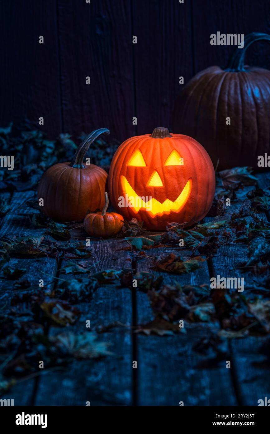 A glowing smiling Jack O' Lantern sitting on an old weathered wooden ...