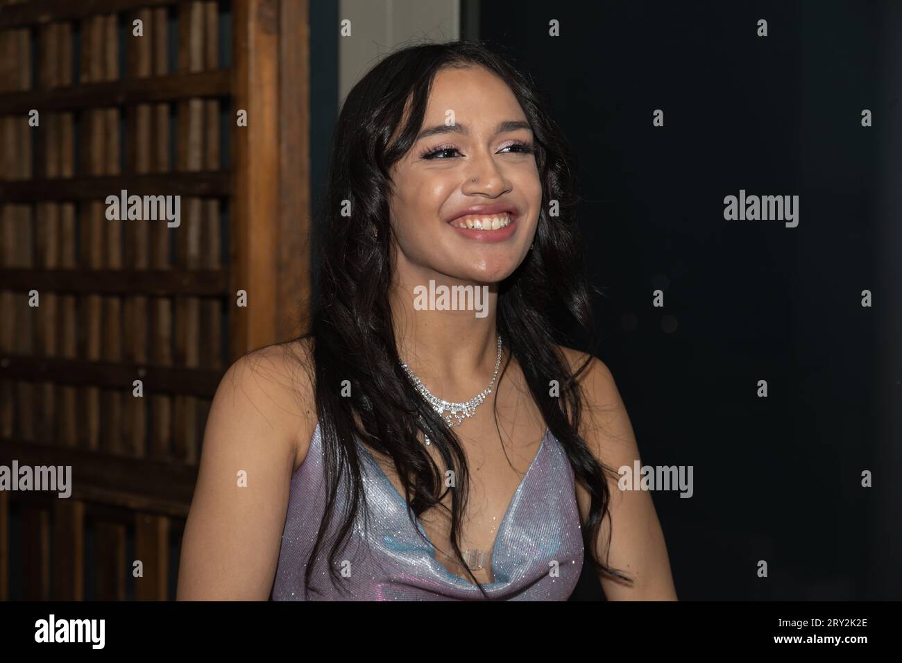 In a close-up, a young woman with long, black straight hair gazes to the side, capturing a candid and enchanting moment at prom Stock Photo