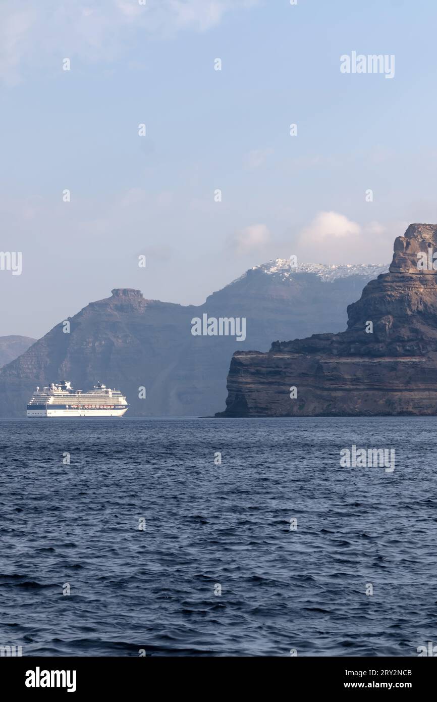 Santorini, Greece - September 7, 2023 : View of a large cruise ship next to the breathtaking volcanic landscape of Santorini Stock Photo