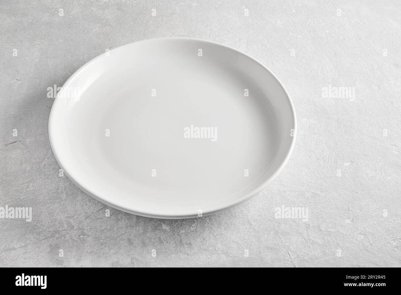 Empty white ceramic plate on gray concrete table high angle view ...