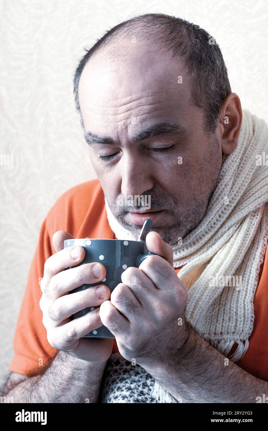 Sick man drinks hotness to recover. The patient holds in his hand a cup