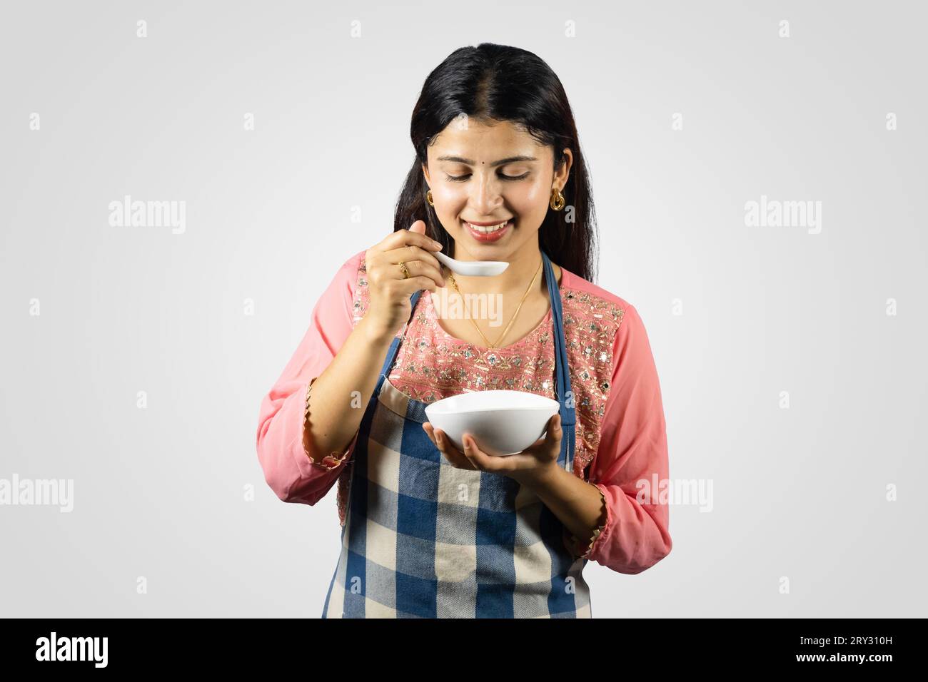 Beautiful Nepalese Indian Housewife in Kurthi, Apron with Kitchen Utensils Smiling, Giving Gestures Stock Photo