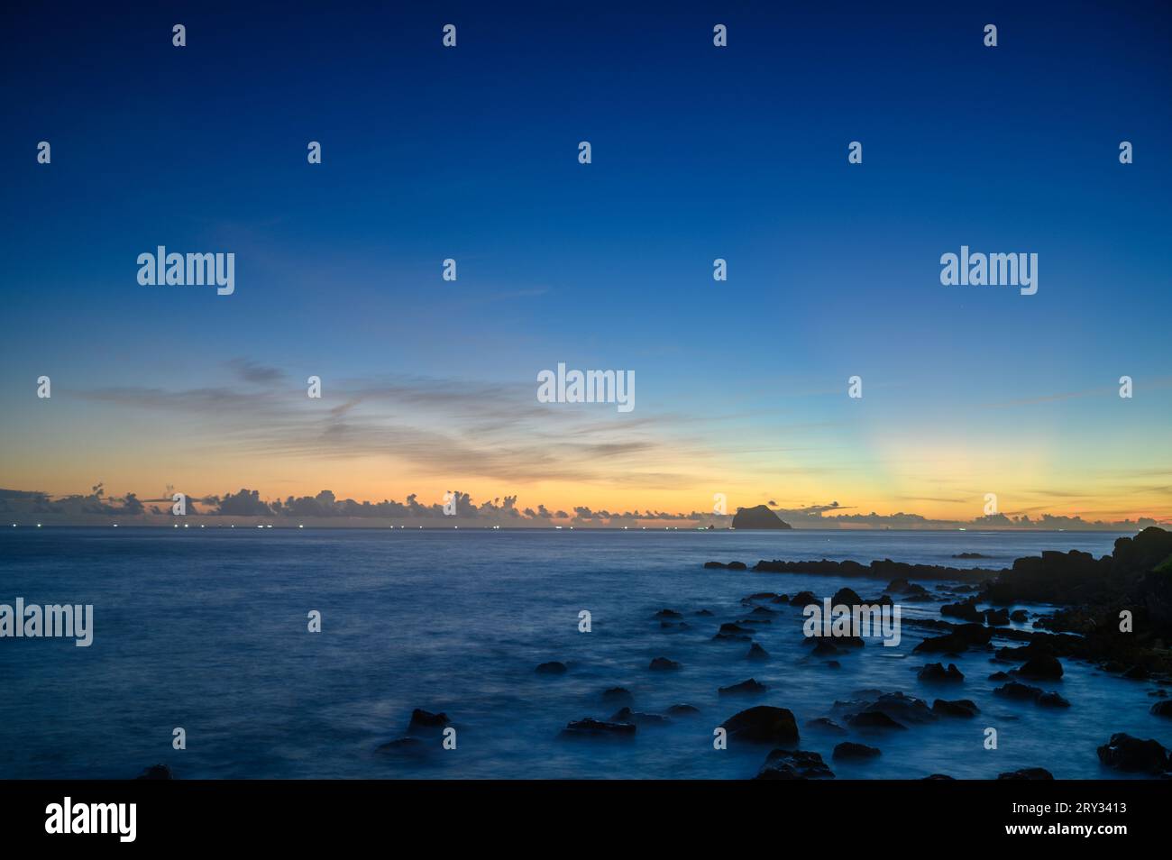 Dawn's Embrace: Sunburst and Rocky Shoreline at the Beach. Enjoy the sunrise view of Keelung Island in the early morning. Stock Photo