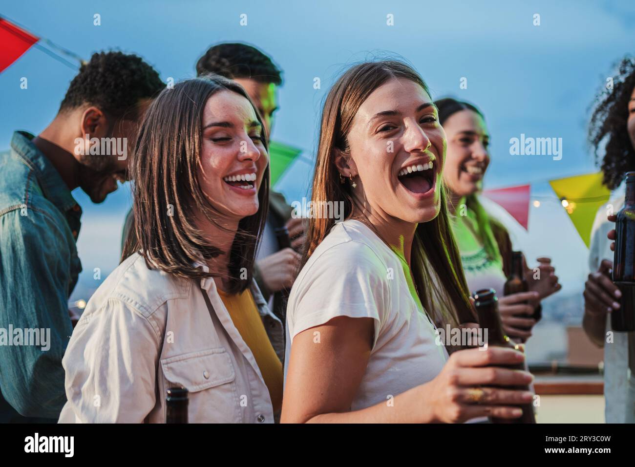 Two excited young adult women dancing together and having fun with friends at music festival. Ecstatic teenage girls celebrating with music on a weekend party. Playful ladies enjoying a birthday event. High quality photo Stock Photo