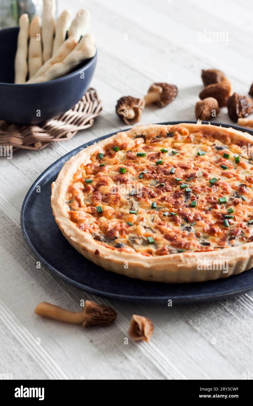 Quiche - open tart pie with morel mushrooms, onion and cheese on a plate Stock Photo