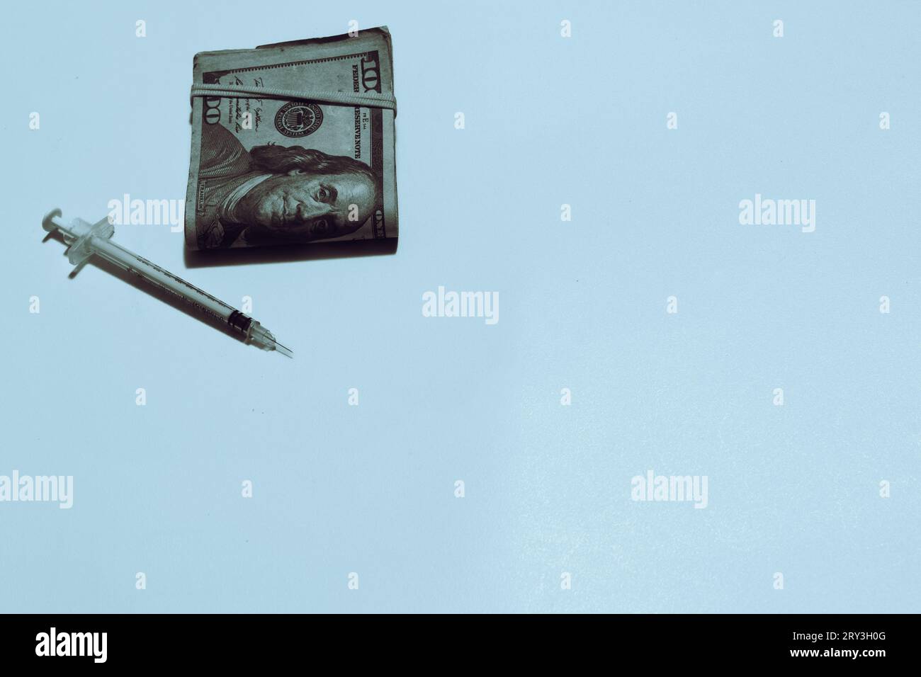 Drug syringe and money on white background with copy space to the right side. Stock Photo