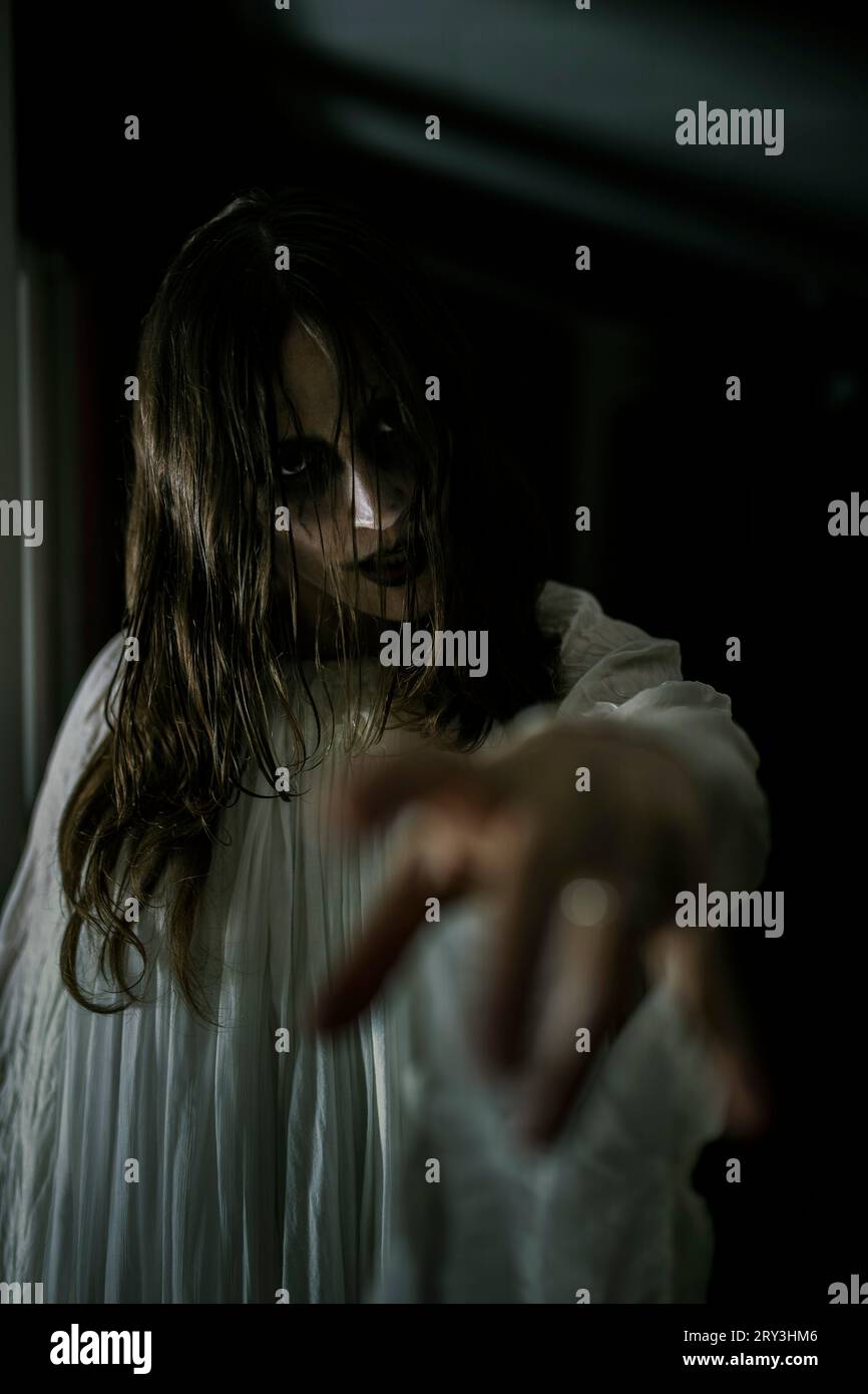 Spooky female ghost reaching out at cabin Stock Photo