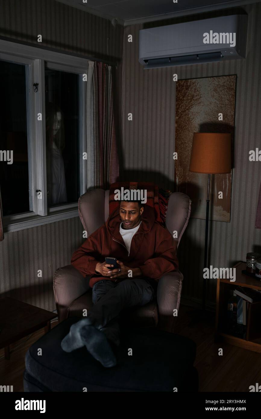 Ghost looking through window at man using smart phone in cabin Stock ...