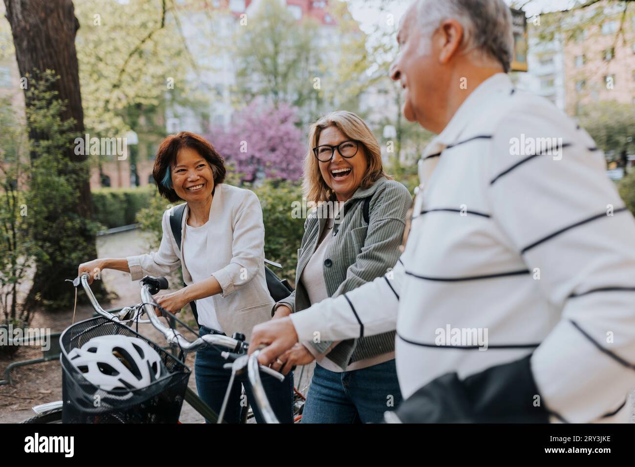 Happy male and female senior friends with bicycles at park Stock Photo