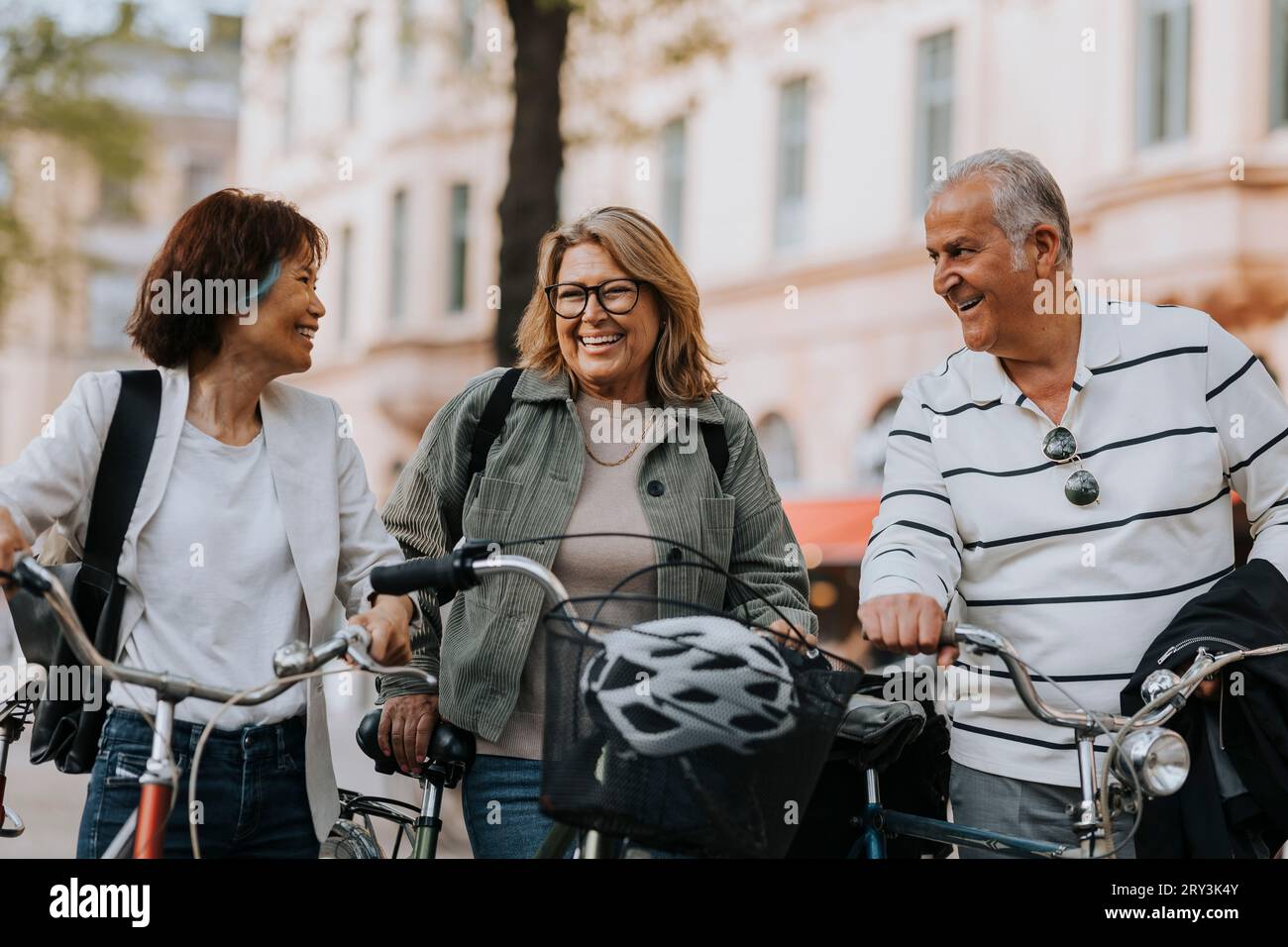 Happy male and female senior friends with bicycles on footpath Stock Photo