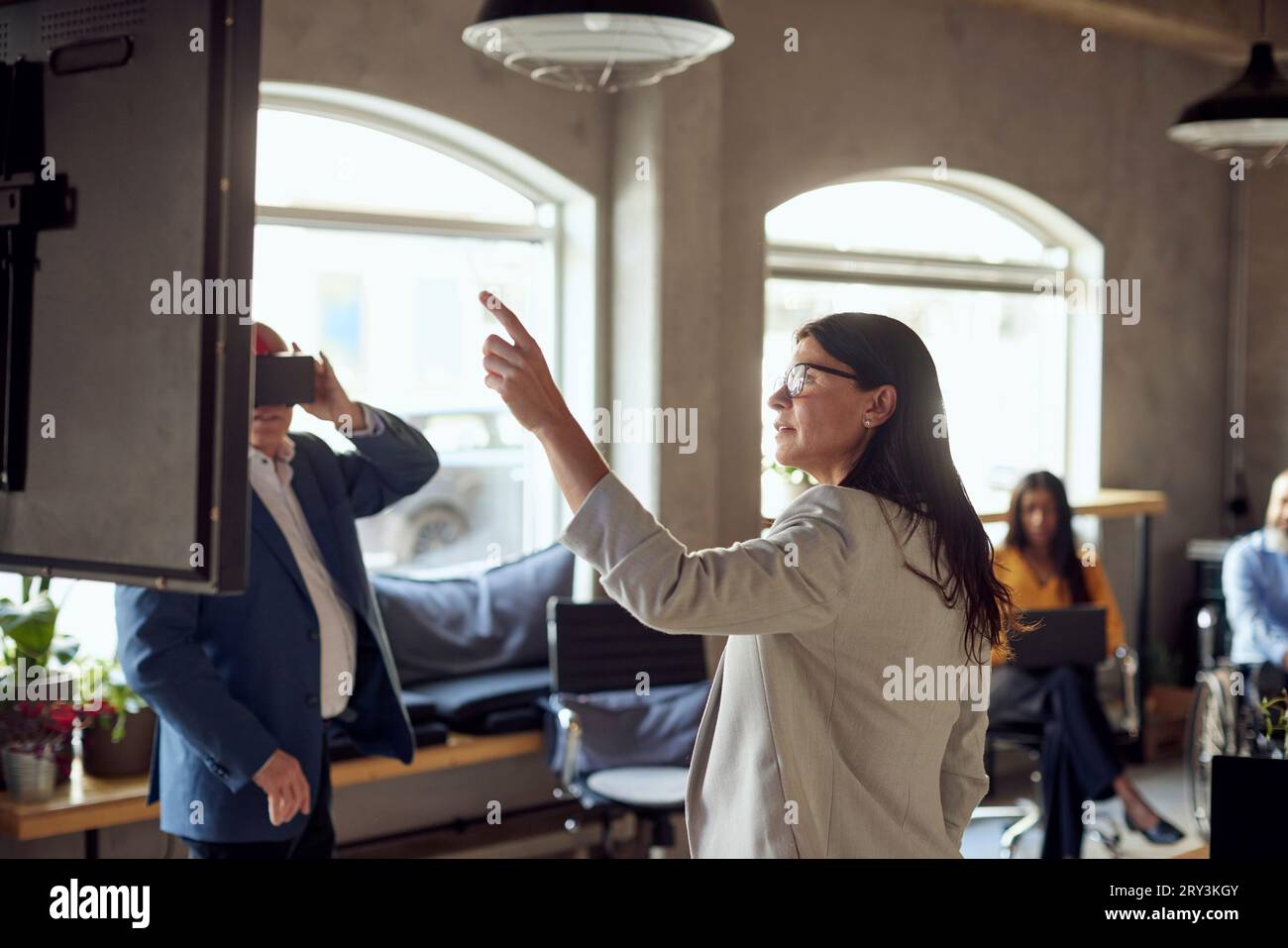 Businesswoman gesturing by businessman wearing VR simulator at office2 Stock Photo
