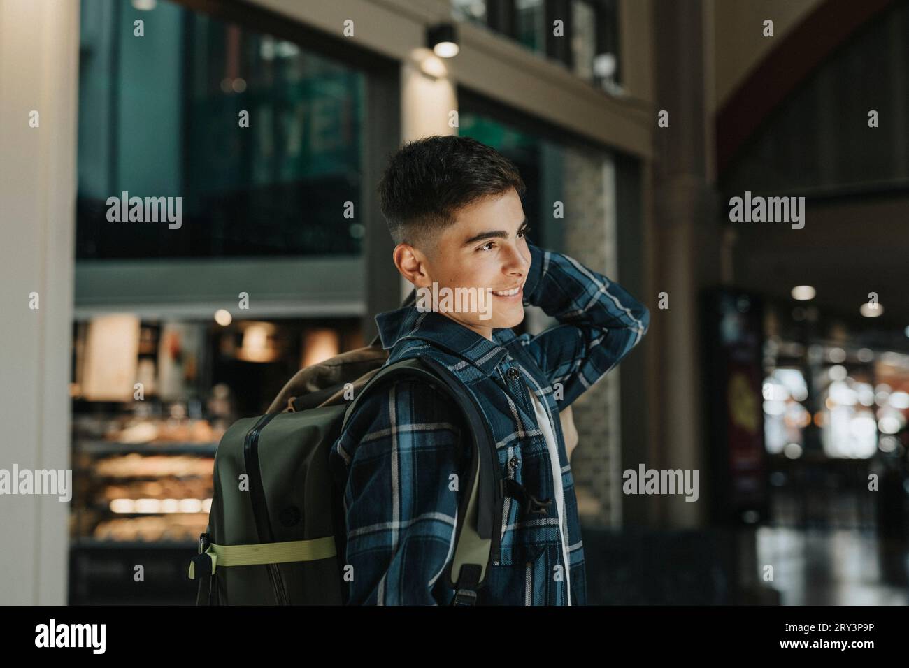 Smiling teenage boy carrying luggage while standing at station Stock