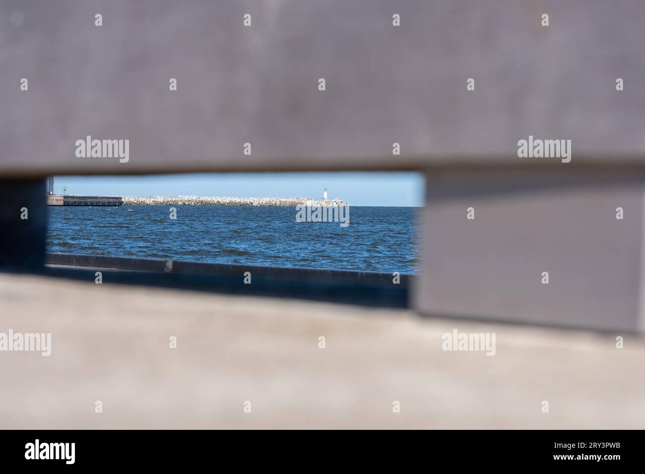 A concrete structure with a rectangular hole as a window through which a mobile floating platform can be seen in the sea. Copy space. Background for q Stock Photo