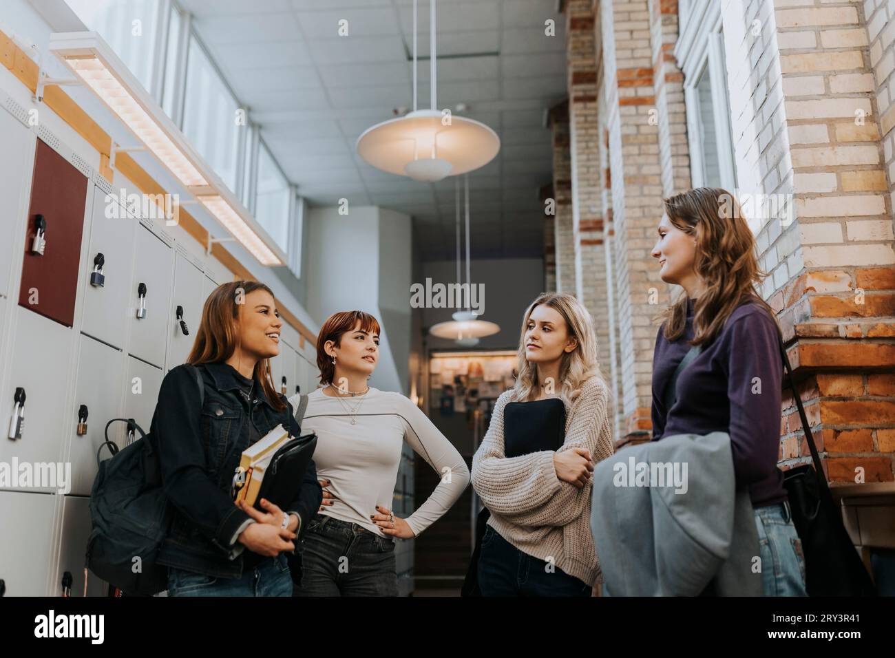 Female students talking while standing in school corridor Stock Photo ...