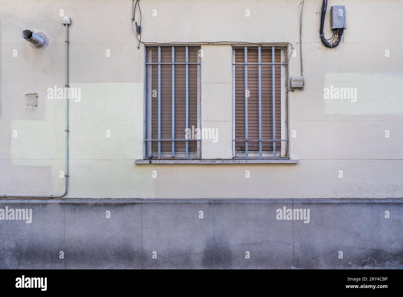 A cement wall with a double window with a gray painted cross grille Stock Photo