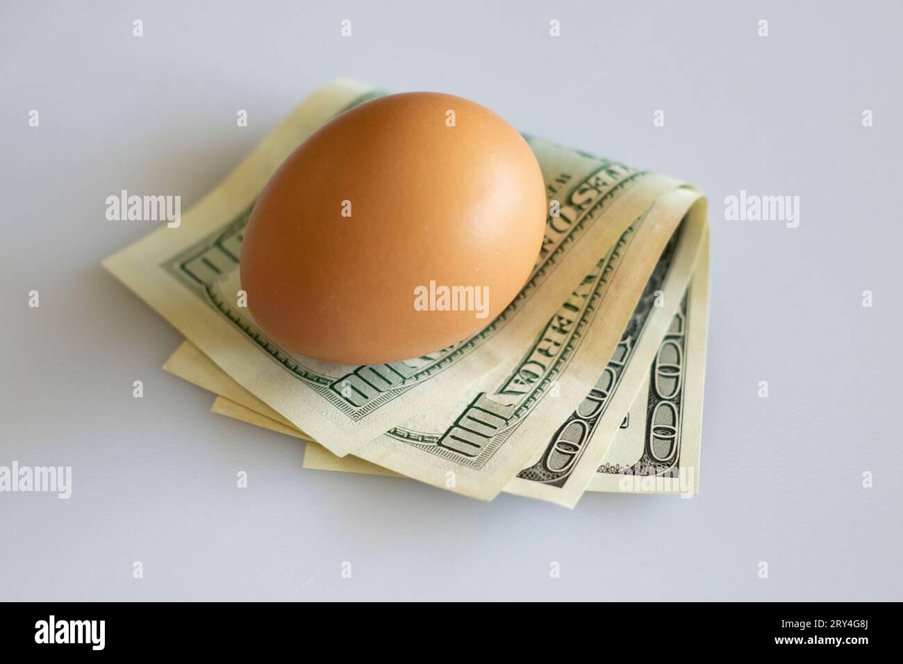 Egg on dollars concept symbolizing the fragility of the economy, markets and savings. Stock Photo