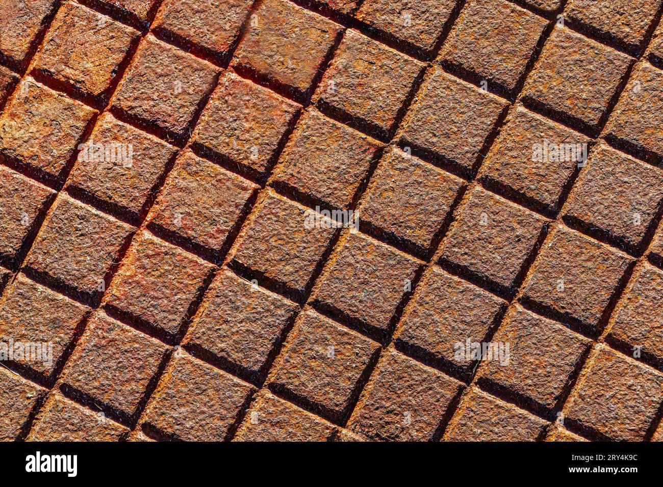 Rusty metal surface with a square grid pattern, industrial background texture. Stock Photo