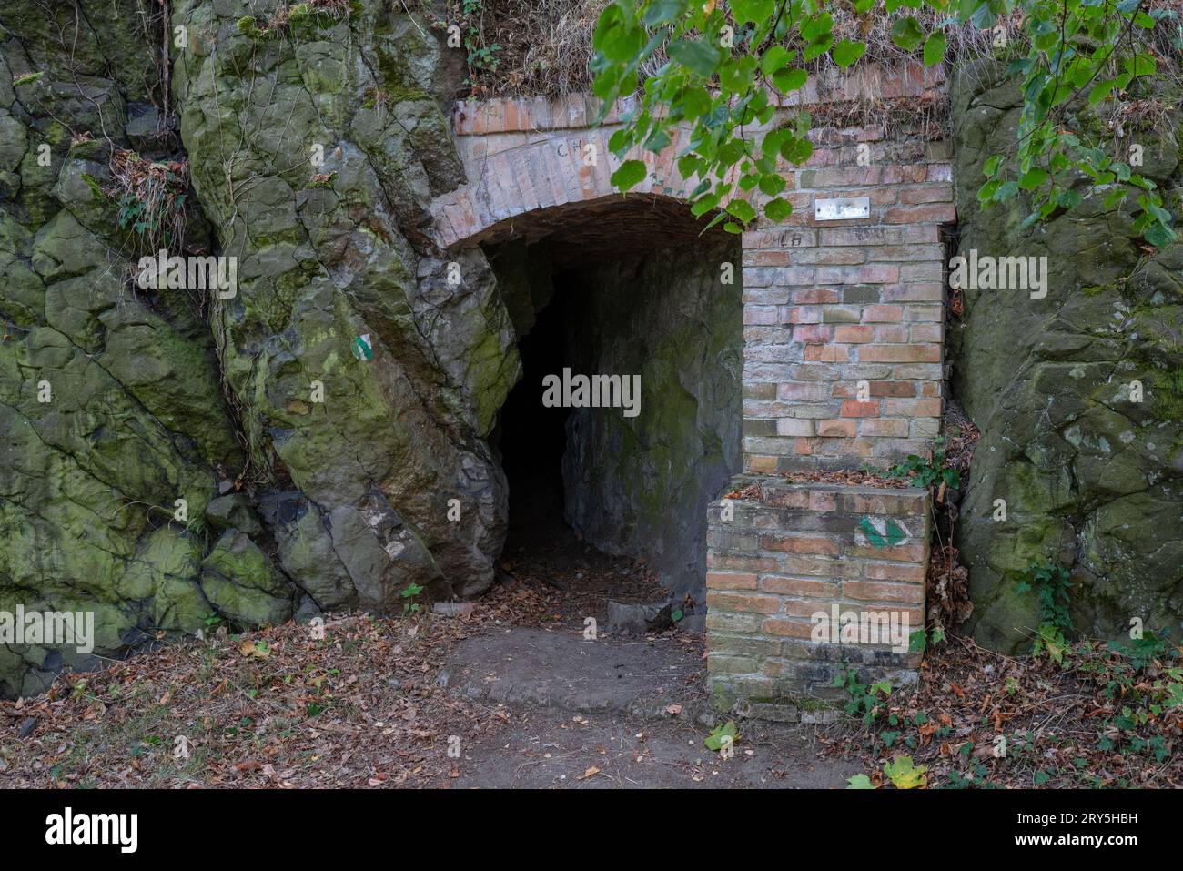 Entrance portal into an adit in basalt, reinforced with bricks. Combination of pseudokarst and selective basalt mining at 'Slánská hora' hill,Czechia. Stock Photo