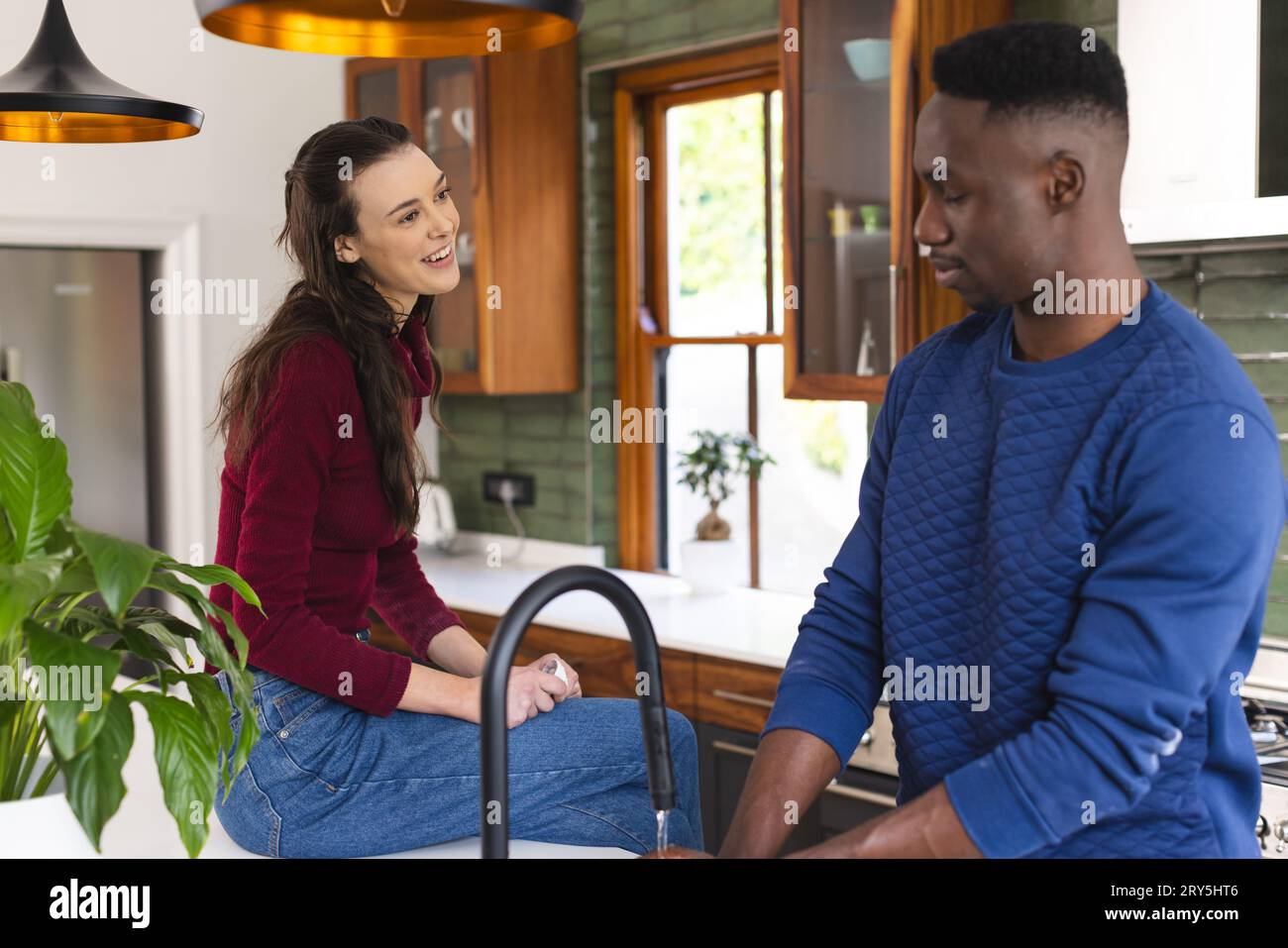 Happy diverse couple talking in kitchen at home Stock Photo