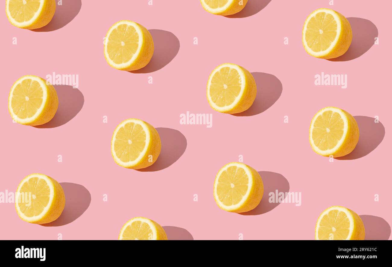 Trendy sunlight summer fruit pattern made with yellow lemon slice on bright light pink background. Minimal summer concept. Creative food idea. Stock Photo