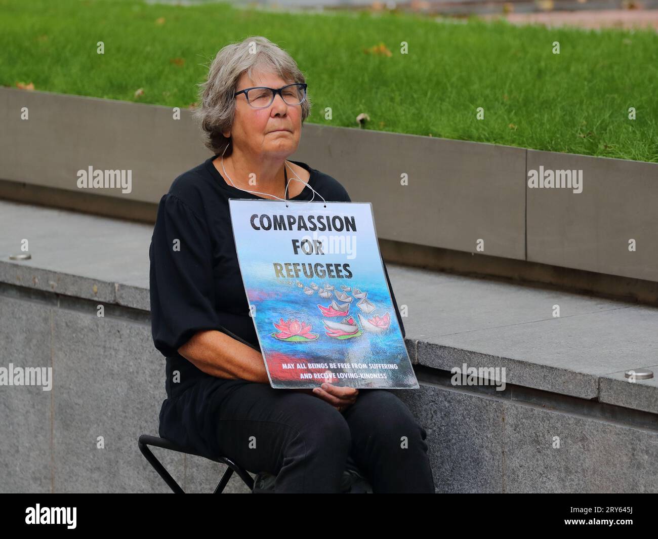 A woman sitting in front of the Home Office holding a placard in support of refugees, London, UK Stock Photo