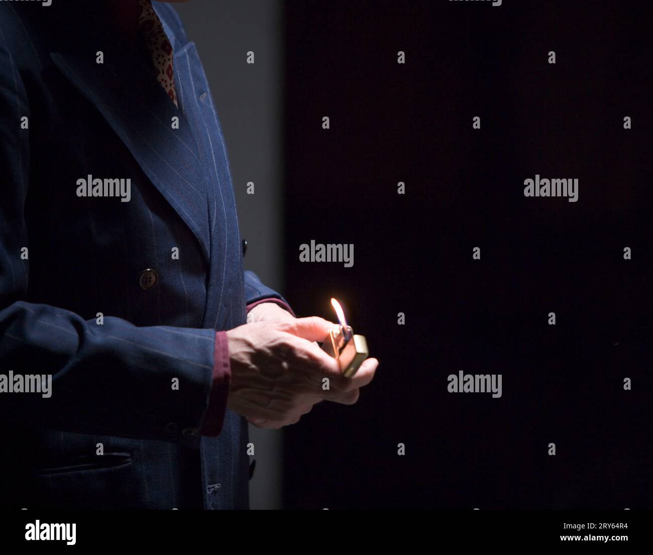 A man's hands holding a lighter with a flame. Stock Photo