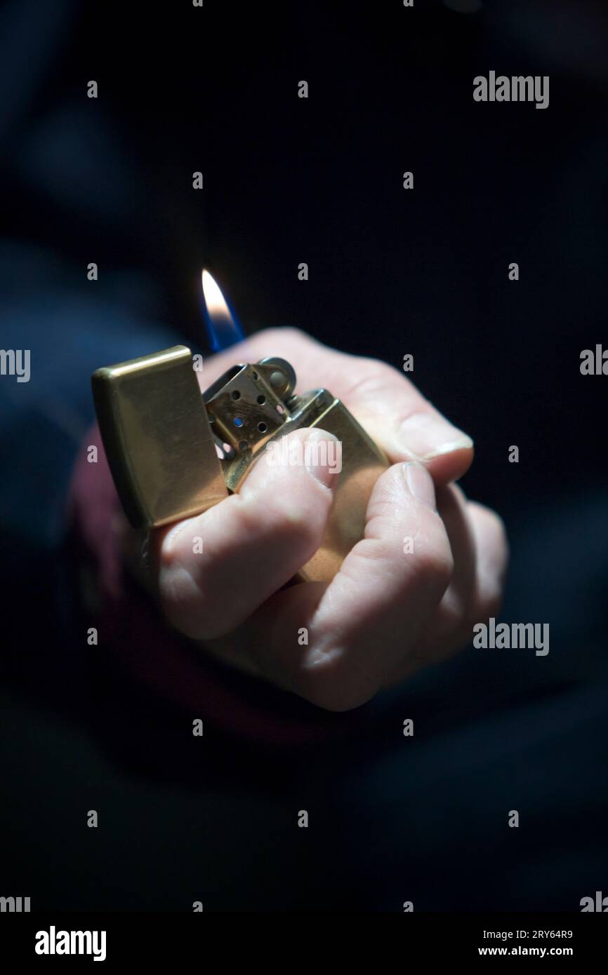 Close up of man's hand holding a lighter with a flame. Stock Photo