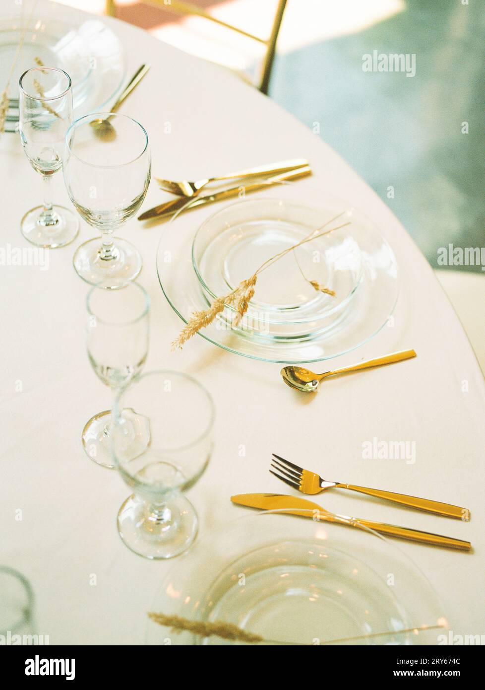 Modern minimalist place setting with clear glass plate, gold fla Stock Photo