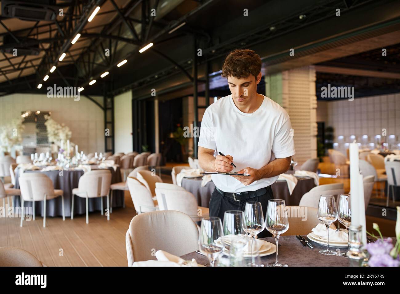 event decorator making notes on clipboard near tables with festive