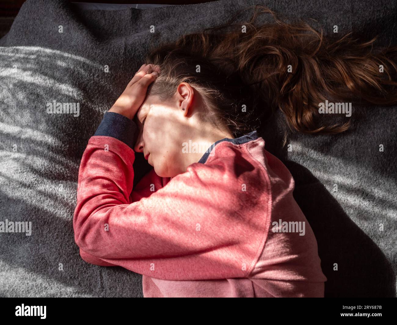 Stressed tired exhausted millennial woman on bed eyes closed suffers from headache.Mental health Psychology Low self-esteem Stress Mindfulness Anxiety Stock Photo