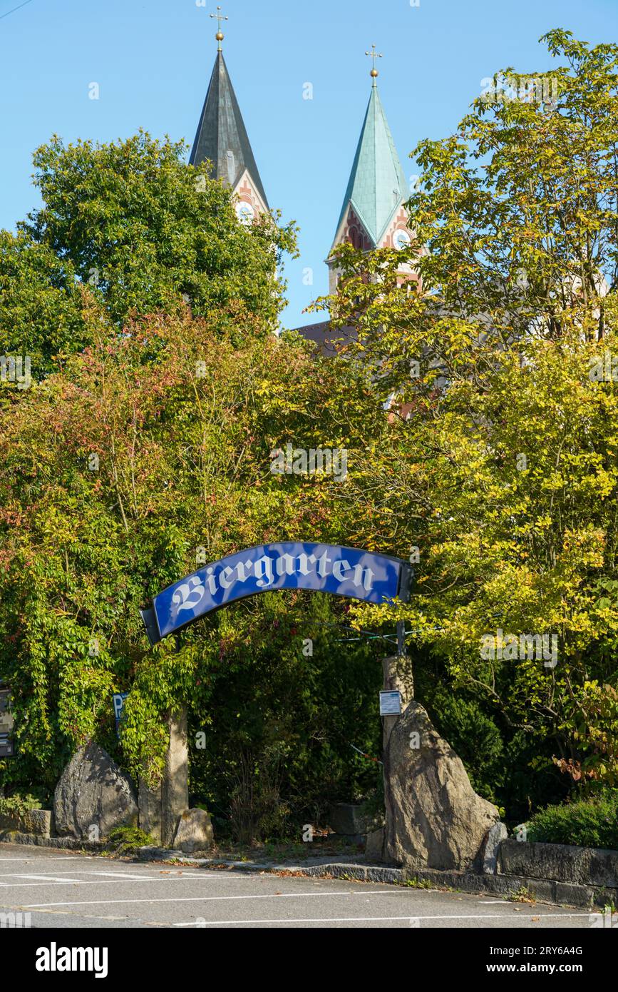 Entrance to a Beer garden with lettering and sign under trees and church. Stock Photo