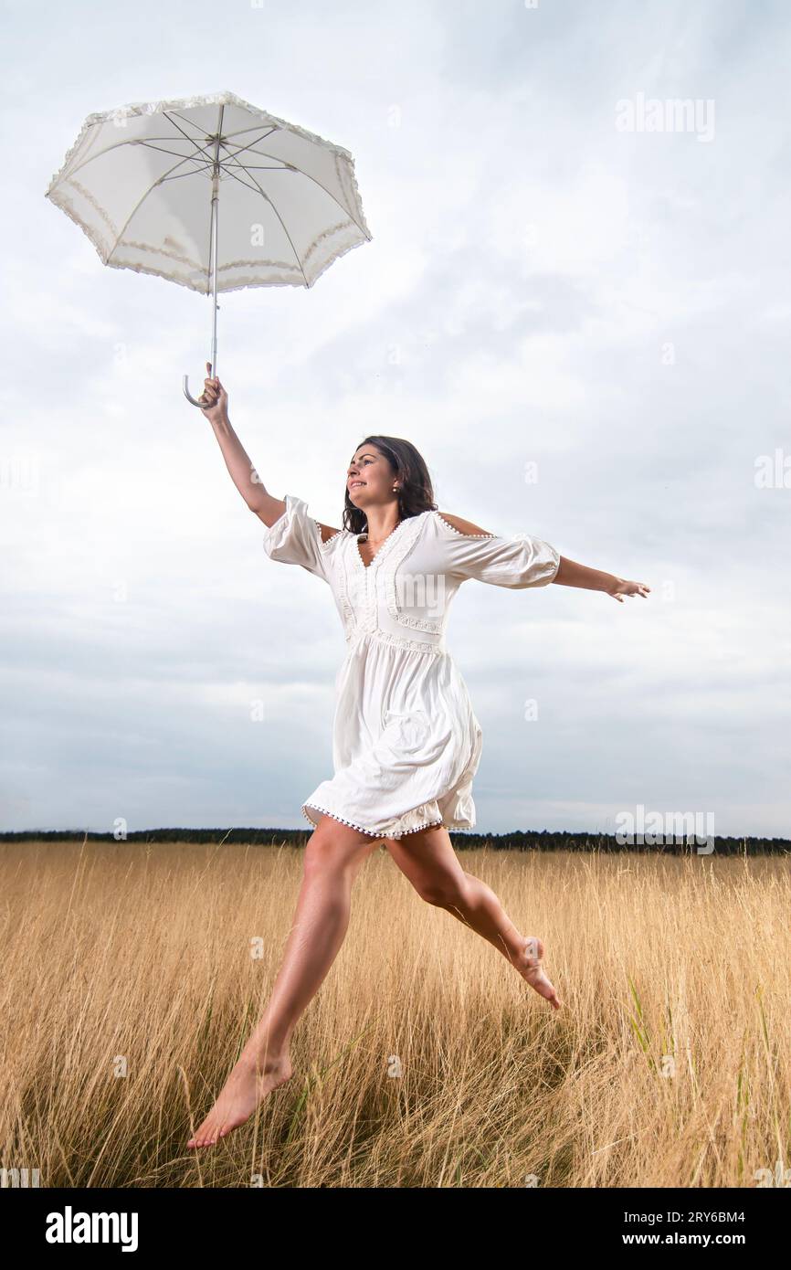 Young fiancee jumps for joy with a dress left out on the meadow Stock Photo