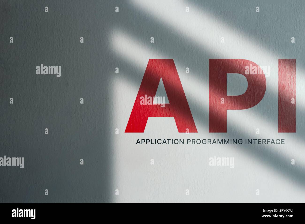 White wall with moody shadows and API word on it and copy space. Application Programming Interface. Software development tool. Internet and networking Stock Photo