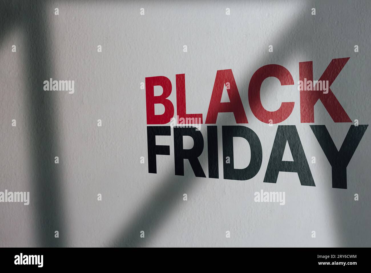 White wall with moody shadows and Black Friday text on it. Online