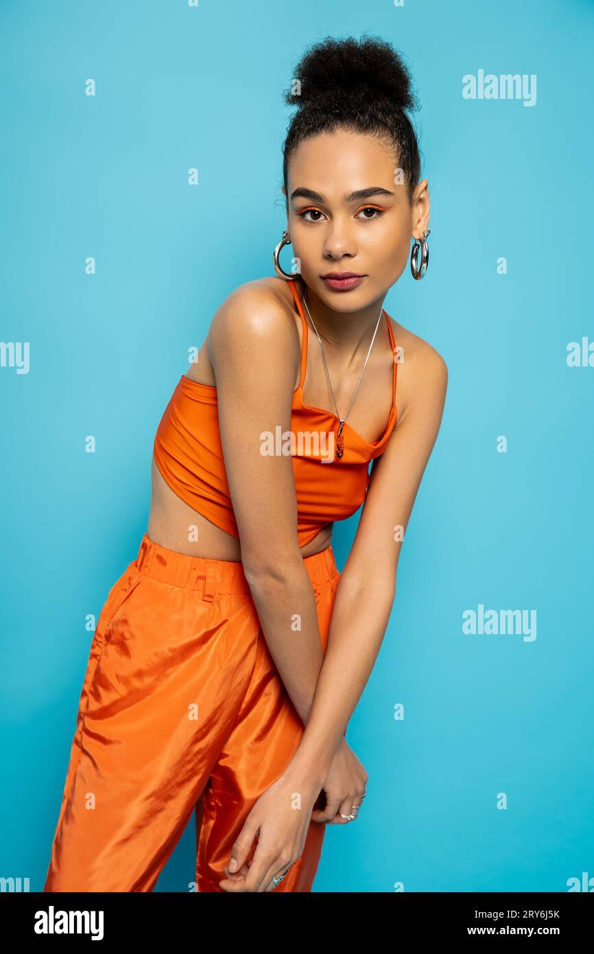 stylish african american model in striking orange outfit with golden ...