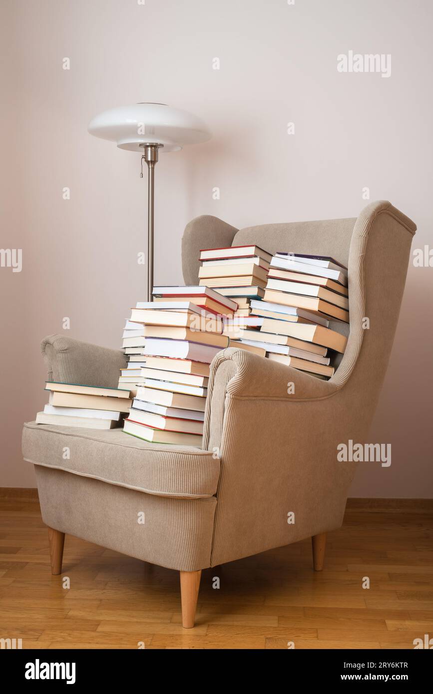 Pile of books on an armchair in reading room Stock Photo