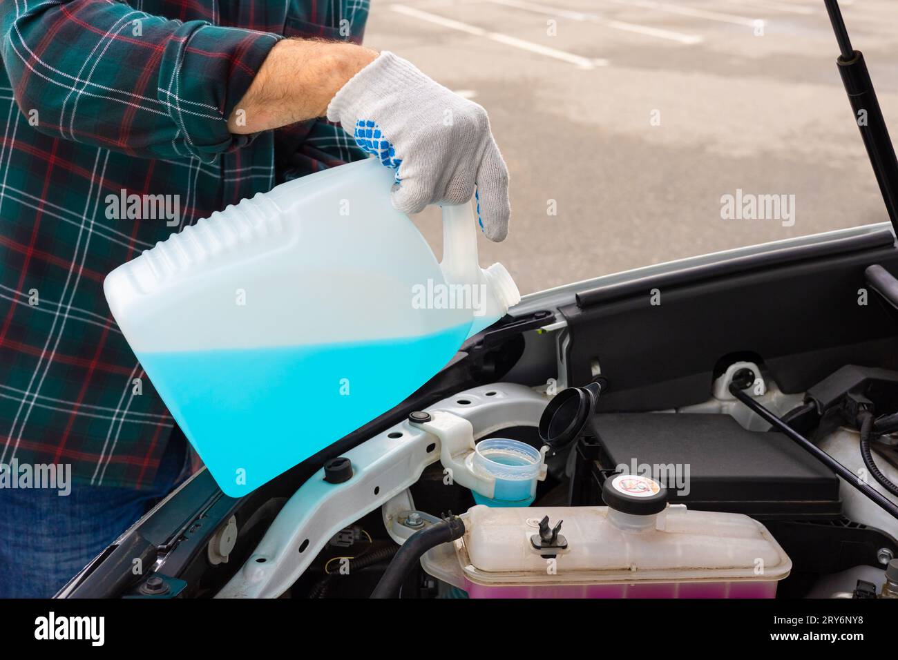 the driver pours fluid into the washer reservoir. washer fluid. glass