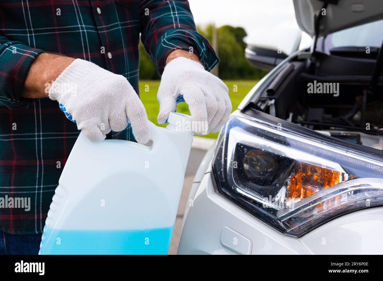 the driver pours fluid into the washer reservoir. washer fluid. glass cleaner. man pouring