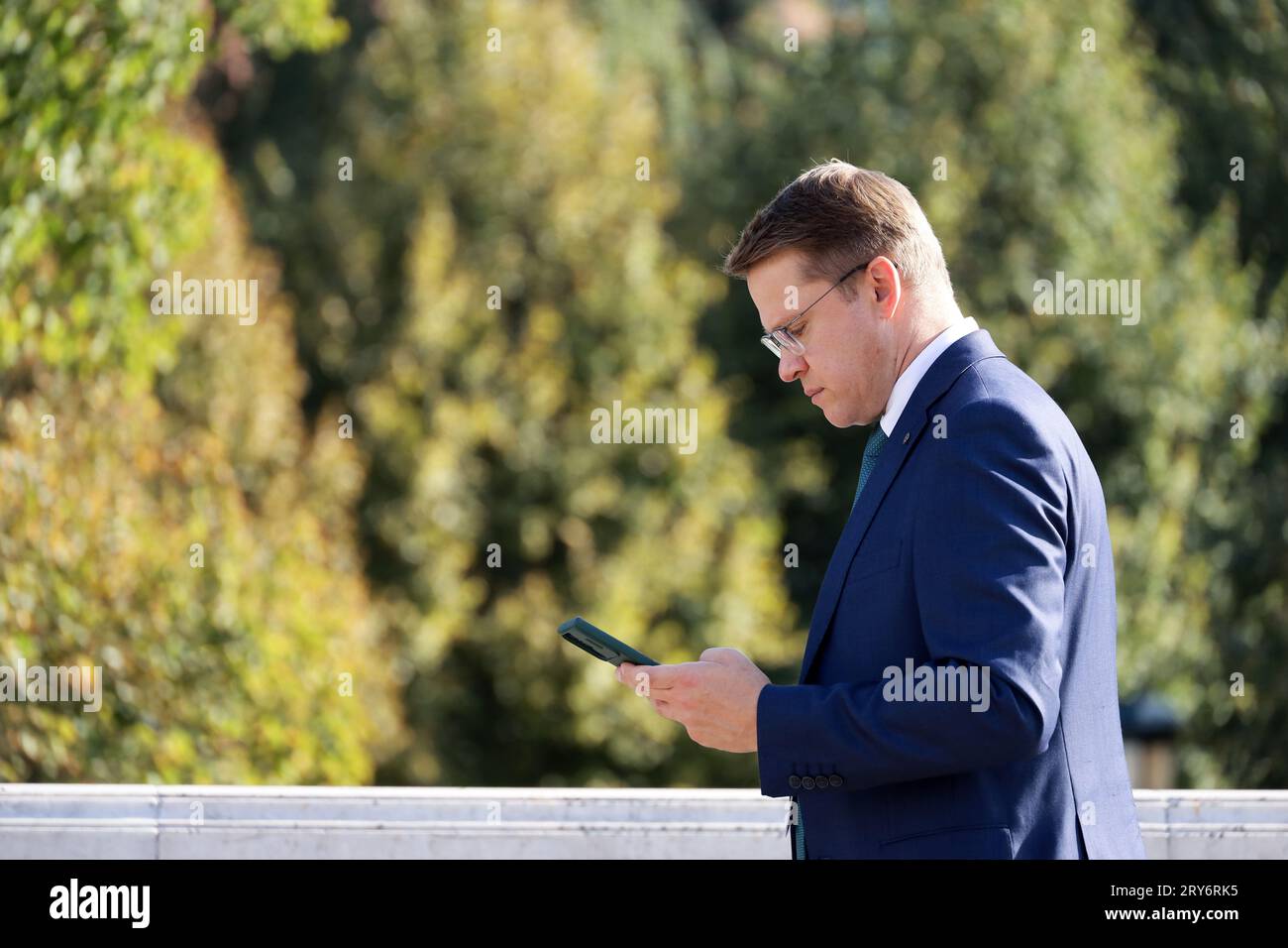 Man in business suit walking with smartphone on city street on park background Stock Photo