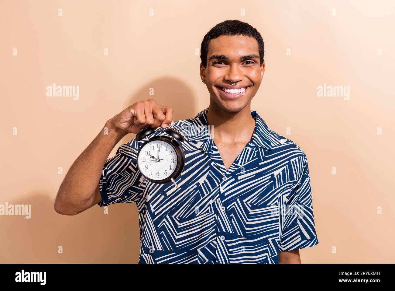 Photo of handsome cool guy dressed print shirt smiling holding clock ...