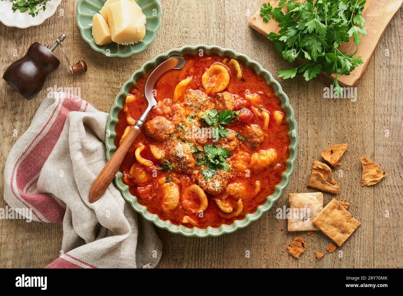 Soup. Fresh tomato soup with meatballs, pasta, vegetables and parsley in green rustic bowl on wooden background. Traditional Italian cuisine. Healthy Stock Photo