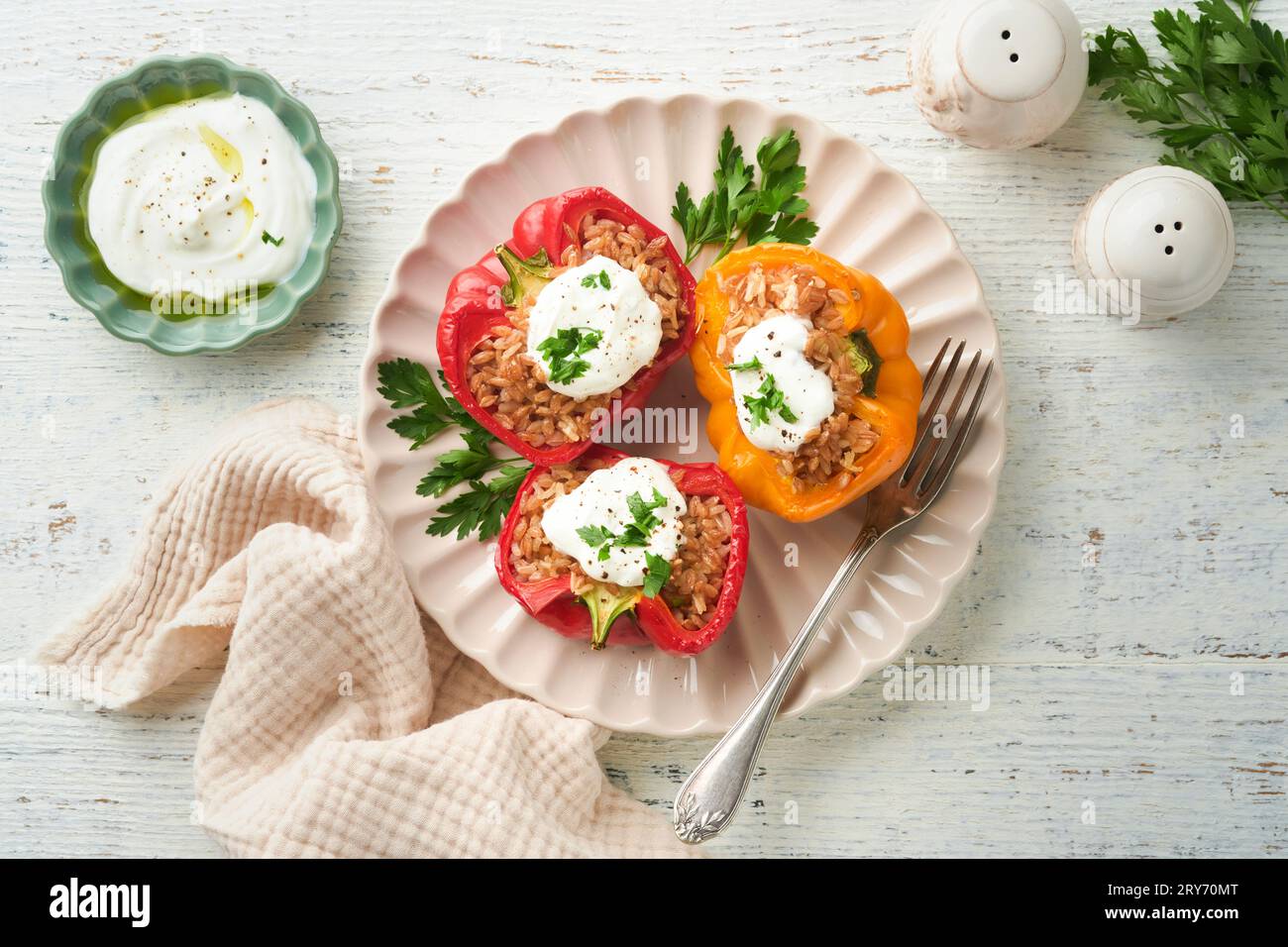 Roast stuffed red and yellow bell peppers with couscous, brown rice and spelled with Greek sauce and olive oil on rustic wooden background. Healthy di Stock Photo